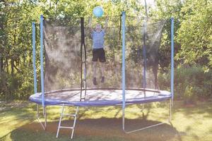 garçon sauter sur trampoline. enfant en jouant avec une Balle sur une trampoline photo