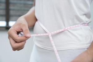 concept de poids perte. fille détient jeans dans sa main et spectacles une mince taille et les mesures sa taille avec une centimètre. régime concept photo