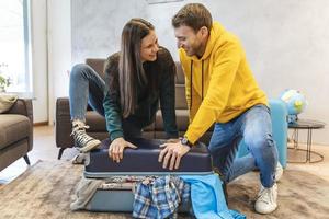 Jeune couple est en train de préparer le les valises pour le suivant voyage photo