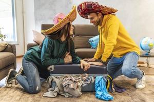 Jeune couple portant sombrero est en train de préparer le les valises pour le suivant voyage photo