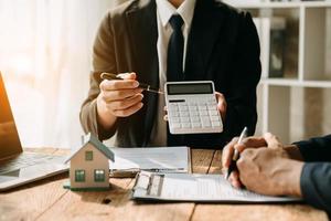 agent de courtage immobilier présentant et consultant le client pour la prise de décision signe un accord de formulaire d'assurance, modèle de maison, concernant l'offre de prêt hypothécaire au bureau photo