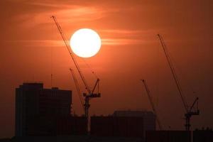 grues et bâtiments se découpant au coucher du soleil photo