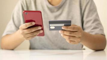 Homme asiatique payant par carte de crédit en ligne lors de la commande sur internet à la maison, idée de transaction à l'aide de l'application bancaire mobile photo