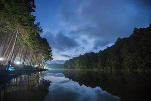 nuages et étoiles au-dessus d'un camping près de l'eau photo