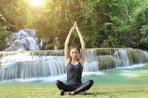 femme asiatique athlétique en pose de yoga avec fond de cascade photo