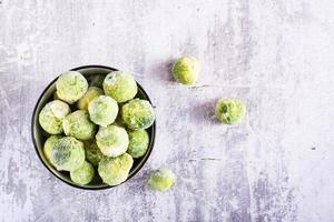 congelé Bruxelles choux dans une bol sur une gris Contexte. végétarien aliments. Haut voir. photo