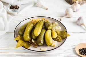 mariné concombres sur une assiette et Ingrédients pour cuisine sur une en bois tableau. fait maison apéritifs. fermer photo