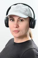 portrait de une fille sur une blanc Contexte avec sans fil écouteurs et une chapeau sur sa diriger. photo