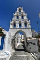 une typique pavé rue avec un arqué cloche la tour dans le traditionnel village de mégachore dans Santorin, Grèce. photo