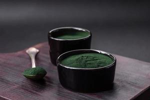 pimenter, vert Couleur spiruline dans le forme de poudre dans une noir bol photo