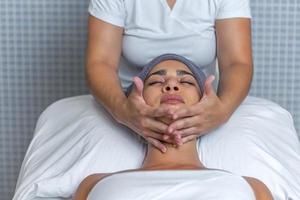 esthéticienne performant une faciale massage avec crème sur une détendu femme visage à santé spa photo