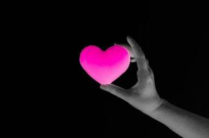 femme main en portant Vide rose cœur sur foncé arrière-plan, symbole de l'amour ou sortir ensemble photo