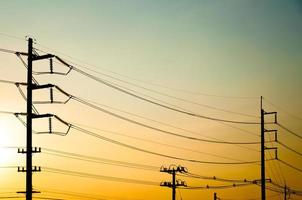 silhouette de électrique pôle avec câble sur spectaculaire le coucher du soleil ciel, horizontal Cadre photo