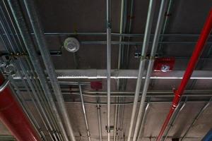 tuyaux de système sanitaire et câbles électriques installés sous une structure en béton armé de dalles plates dans le bâtiment.tuyaux de ventilation dans un parking souterrain photo