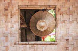 magnifique local Fait main asiatique chapeau sur surface de bambou pendaison sur le fenêtre de une bambou maison. photo