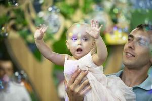 papa journée. papa pièces avec le sien peu fille sur le Contexte de savon bulles. photo