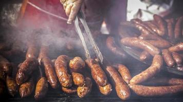 une fermer vue de mains de une homme grillage fait maison saucisses photo