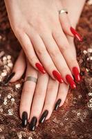 mains d'une jeune fille avec une manucure rouge et noire sur les ongles photo