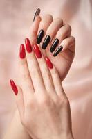 mains d'une jeune fille avec une manucure rouge et noire sur les ongles photo