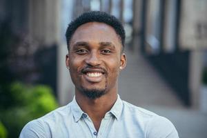 portrait de une Jeune de bonne humeur africain américain homme à la recherche à le caméra, souriant et réjouissance photo