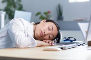 Jeune asiatique femme d'affaires est tombée endormi à le bureau sur sa mains dans le Bureau photo