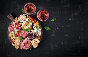 antipasto plat avec jambon, prosciutto, salami, bleu fromage, mozzarella avec Pesto et Olives sur une en bois Contexte. Haut voir, aérien photo