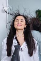 belle jeune femme utilisant un sèche-cheveux dans un salon de coiffure. gros plan des cheveux de la femme dans un salon de beauté, concept de coiffure photo