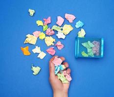 femelle main détient une bouquet de froissé multicolore pièces de papier photo