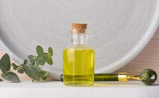 bouteille en verre transparent avec huile jaune et branche d'eucalyptus, produit cosmétique photo