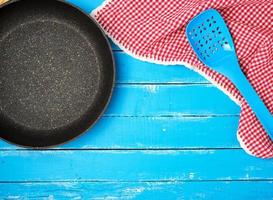 vide noir rond antiadhésif friture la poêle avec manipuler sur bleu en bois Contexte photo