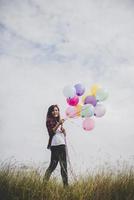 belle jeune femme hipster tenant des ballons colorés à l'extérieur photo