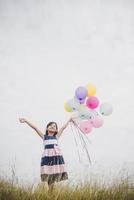 petite fille jouant avec des ballons sur le champ de prés photo