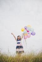 petite fille jouant avec des ballons sur le champ de prés photo