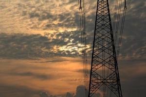 haute tension poteaux sont utilisé à porter électricité pour industriel les plantes et gens à utilisation dans le Les agriculteurs des champs dans le soir. magnifique ciel atmosphère et conçu par électrique ingénieurs. photo