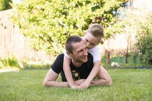 une mignonne bébé est mensonge sur le sien du père dos. mensonge sur le pelouse photo