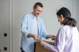 une homme livre une parcelle dans une artisanat emballer, une fille accepte une paquet de une courrier photo