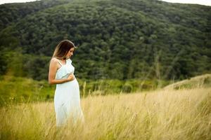 jeune femme enceinte se détendre à l'extérieur dans la nature photo