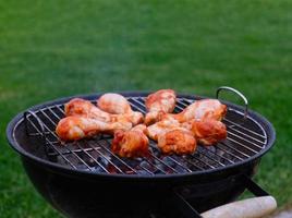 grillé poulet jambes sur le gril. poulet jambes mariné dans barbecue sauce, grillé avec rouge charbons dans le arrière-cour Contexte. rouge charbons et fumée de le Feu. Haut voir. photo