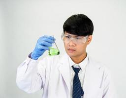 asiatique homme étudiant scientifique ou médecin dans réactif mélange laboratoire dans une science recherche laboratoire avec tester tubes de divers tailles. sur le sol dans laboratoire chimie laboratoire blanc Contexte. photo