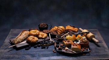 vue de dessus pain frais raisins secs bruns sésame boulangerie à base de farine de blé nourriture maison adaptée à une alimentation saine sur table en bois plancher noir rustique fond sombre photo