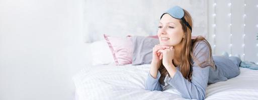 content en bonne santé, magnifique Jeune femme portant sommeil masque et bleu pyjamas, éveillé photo