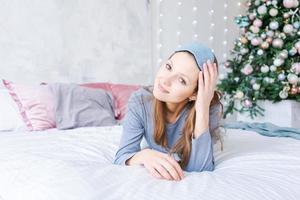 de bonne humeur fille dans en train de dormir œil masque mensonge dans lit dans bleu pyjamas contre photo