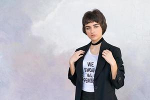 Jeune femme avec court la Coupe de cheveux sur Contexte mur. posant dans blanc T-shirt photo