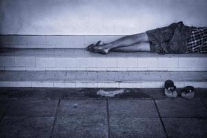 sans abri homme sale dort sur le rue dans le ombre de le bâtiment. photo