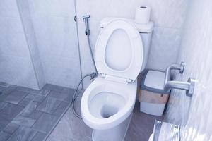 cuvette des toilettes dans une salle de bains moderne avec poubelles et papier toilette, toilettes propres photo