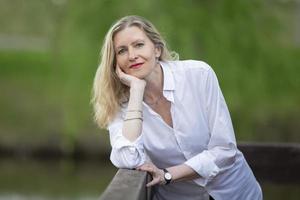 une magnifique âge moyen européen femme. cinquantenaire blond femme dans une blanc chemise sur le Contexte de la nature. photo