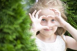 une peu fille spectacles une cœur signe avec sa des doigts. photo