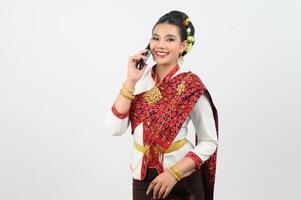 Jeune magnifique femme robe en haut dans thaïlandais nord Région pose avec téléphone intelligent photo