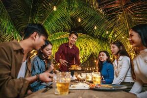 portrait d'amis asiatiques heureux en train de dîner ensemble - jeunes gens grillant des verres à bière dîner en plein air - gens, nourriture, style de vie des boissons, concept de célébration du nouvel an. photo