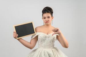 jeune belle mariée asiatique pose avec un tableau blanc à la main photo